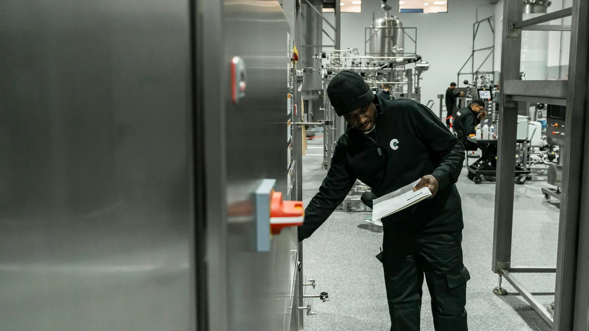 A technician checking stainless plant, clipboard in hand